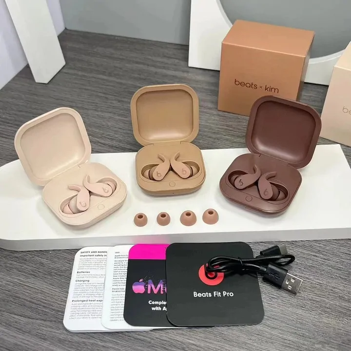 Three small hinged charging cases open on a grey desk, each holding a pair of wireless earbuds, with a cable and a card laid alongside