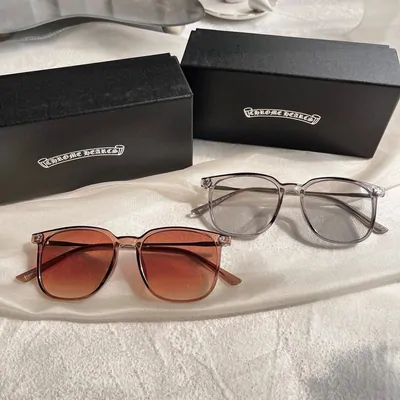 Two pairs of glasses laid in front of their black cases, one with brown-tinted lenses and one with clear round lenses