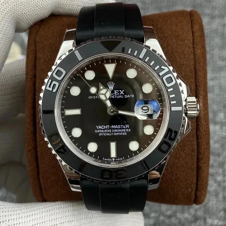 A diver-style watch with a black dial and rubber strap, sitting in a brown presentation box, the bezel numbered around its edge