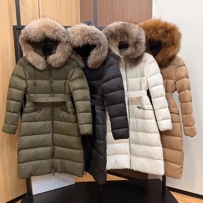 Four long hooded down coats hanging on a rail with fur-trimmed hoods, in olive, black, cream and tan